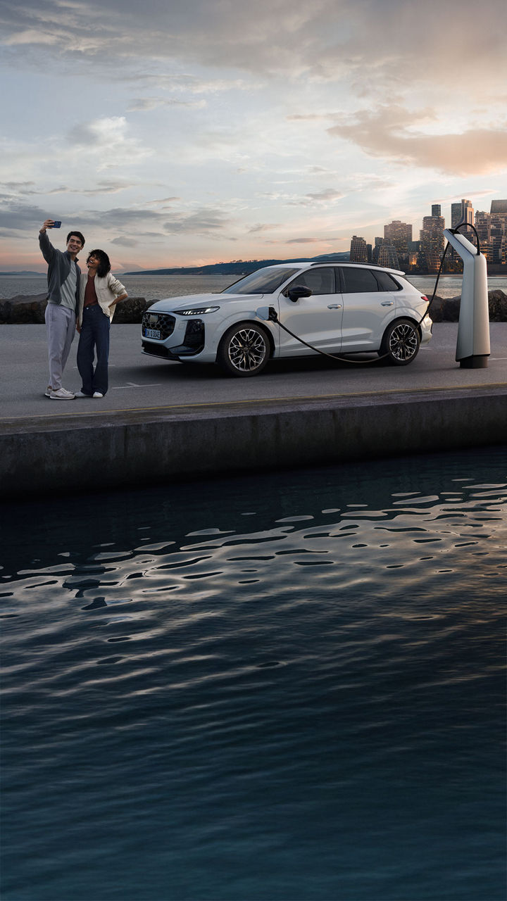 Side view of Audi Q3 SUV e-hybrid charging in a parking lot