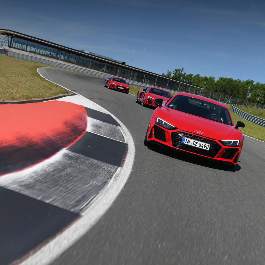 Drei rote Audi R8 Coupé V10 performance quattro fahren hintereinander auf einer Rennstrecke