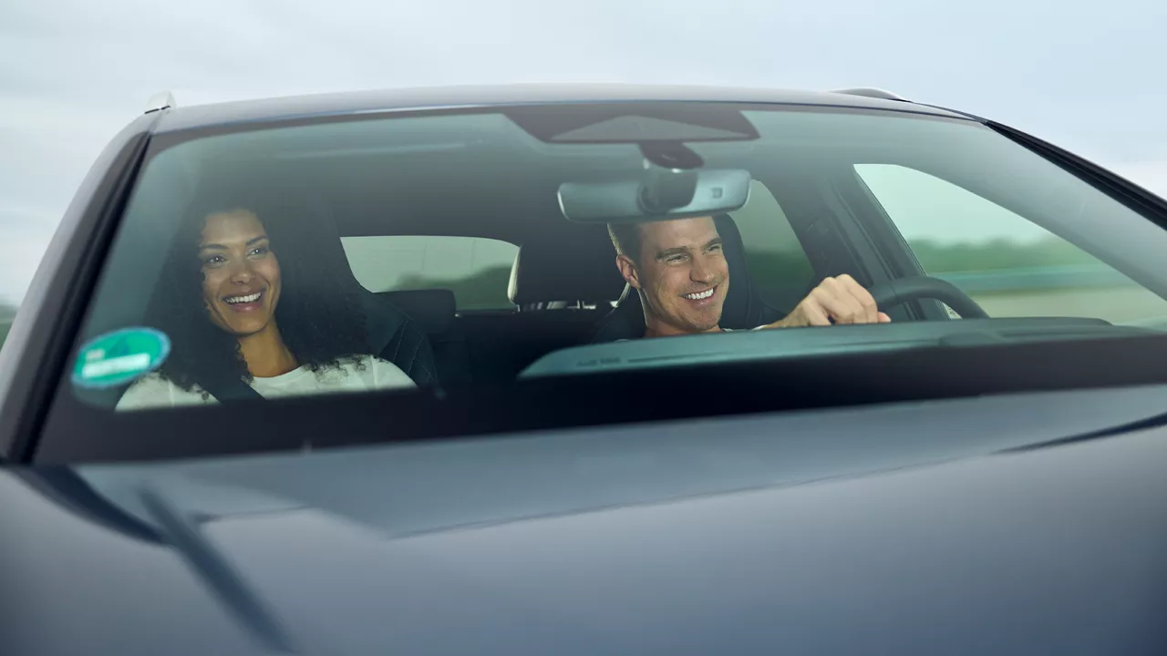 Mann und Frau sitzen in einem Audi Modell, der Mann sitzt am Steuer, beide lächeln
