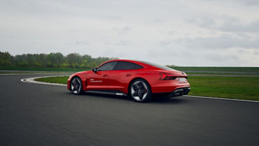 A red Audi model drives on the race track.
