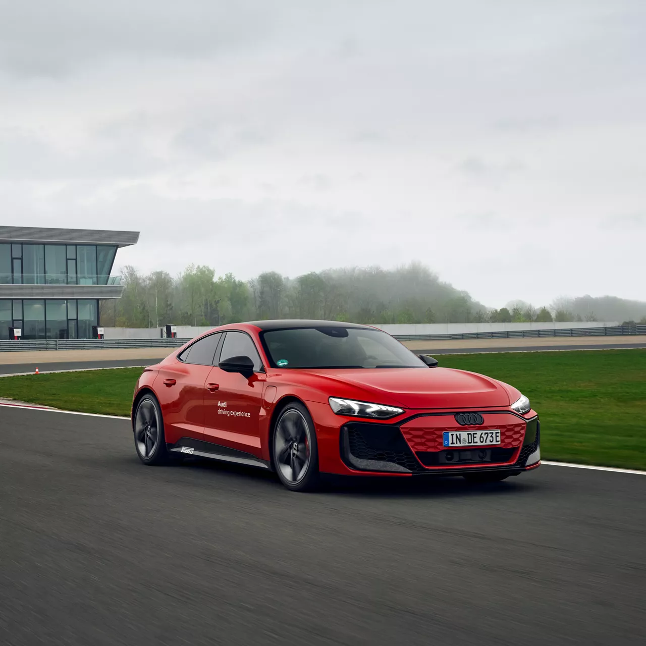 Roter Audi RS e-tron GT peformance fährt auf einer Strecke in Neuburg, im Hintergrund befindet sich ein großes Gebäude