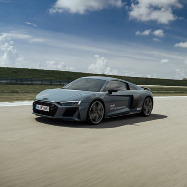 Mattgrauer Audi R8 Coupé V10 plus performance fährt auf einer Strecke