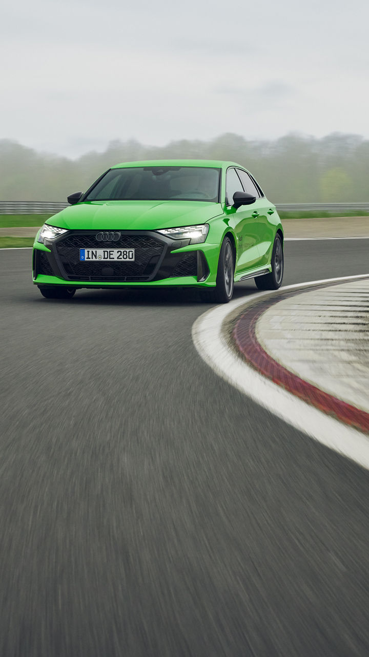Hellgrüner Audi RS 3 Sportback fährt in einer Kurve auf einem Übungsgelände