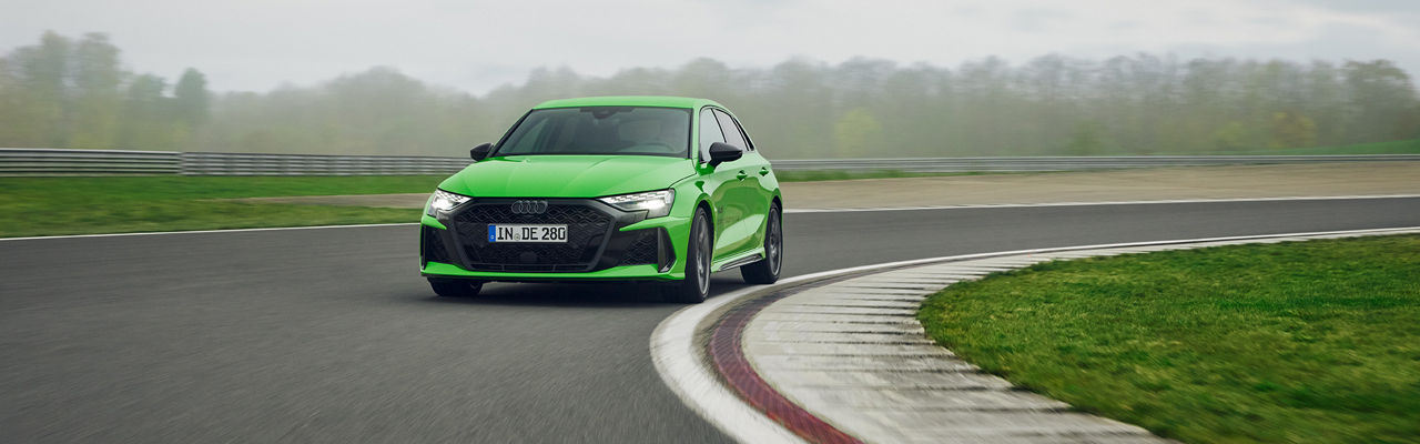 Hellgrüner Audi RS 3 Sportback fährt in einer Kurve auf einem Übungsgelände