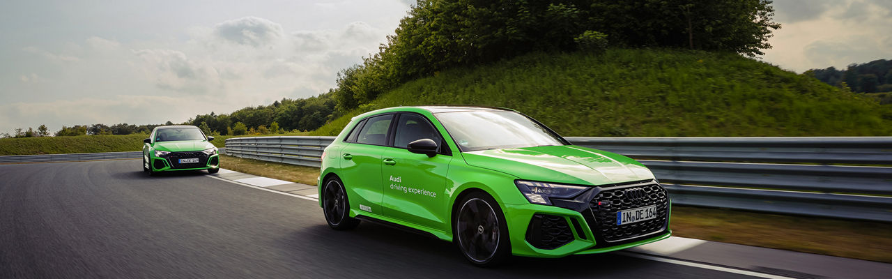 Zwei hellgrüne Audi RS 3 Sportbacks fahren auf einer Rennstrecke hintereinander
