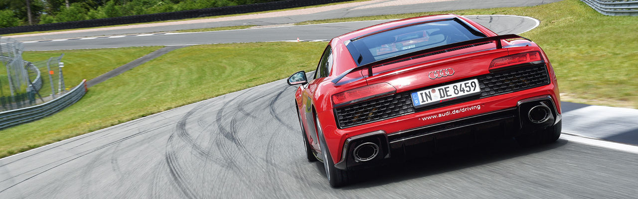 Roter Audi R8 Coupé von der Rückansicht fährt auf einer Rennstrecke
