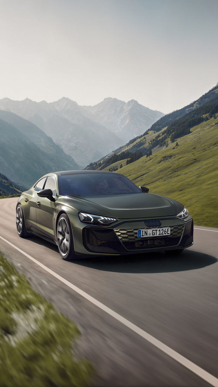 Dark green Audi RS e-tron GT performance drives on a road in the mountains