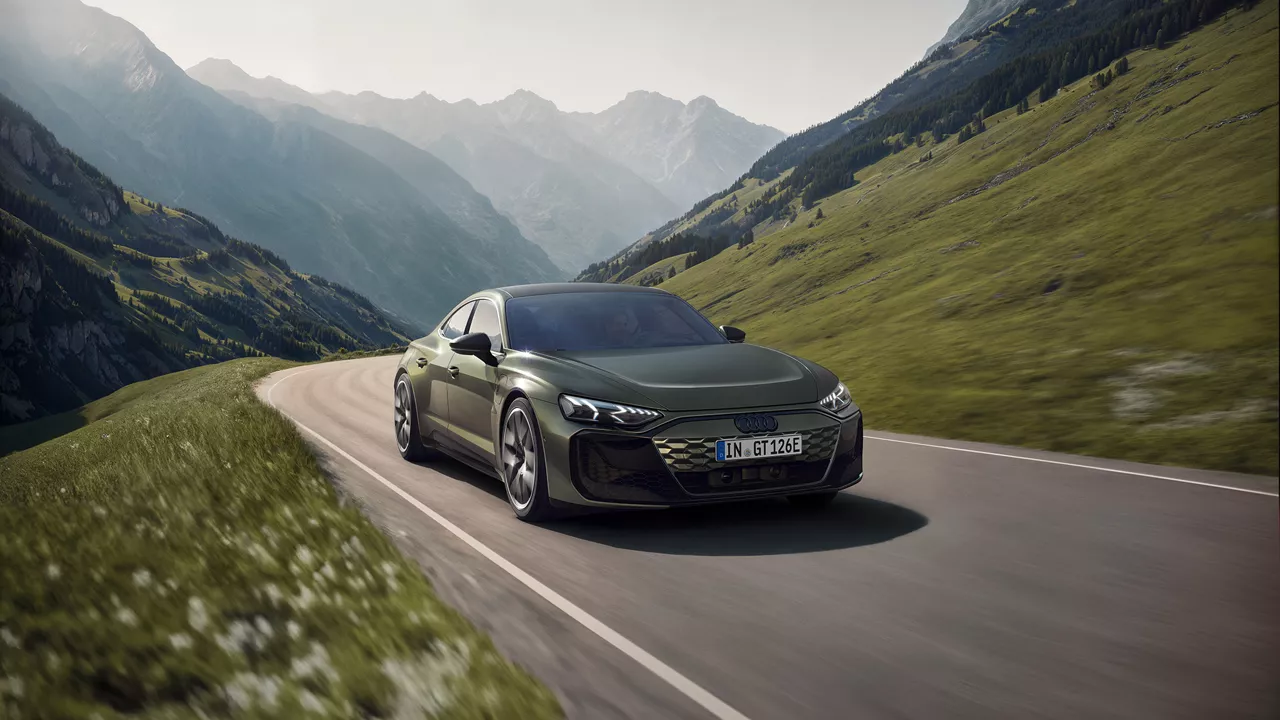 Dark green Audi RS e-tron GT performance drives on a road in the mountains