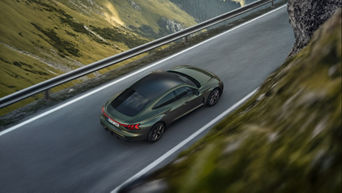 A bird's eye view of a dark green Audi RS e-tron GT driving on a road in the mountains.