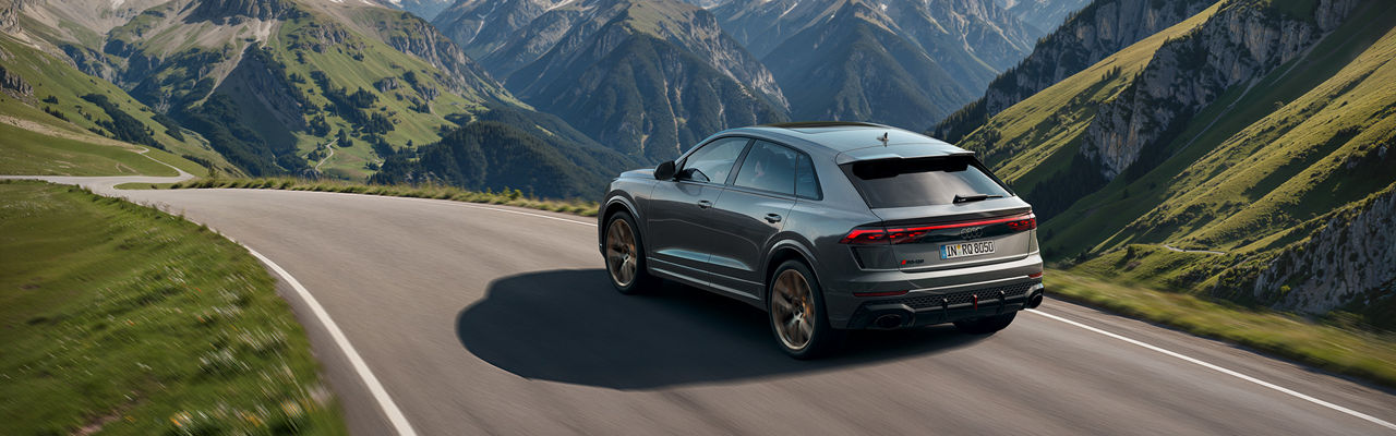Silberner Audi RS Q8 SUV fährt durch die Berge (Rückansicht)