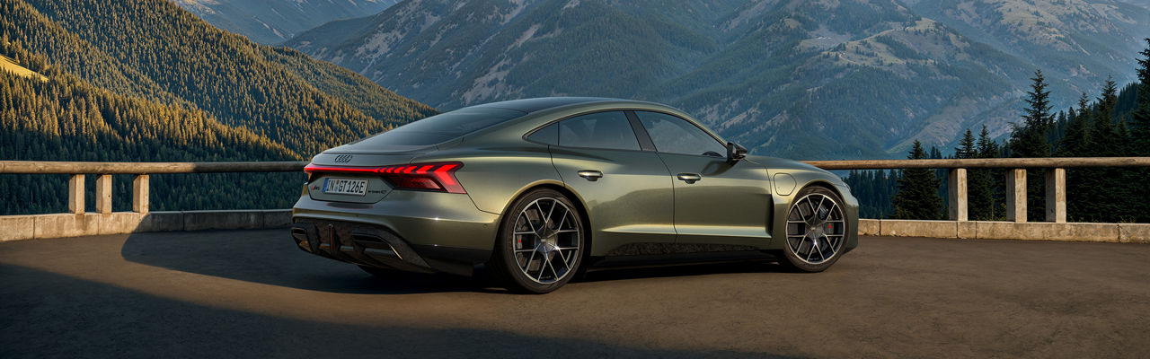 Dunkelgrüner Audi RS e-tron GT performance steht vor einer bergigen Landschaft bei sonnigem Wetter