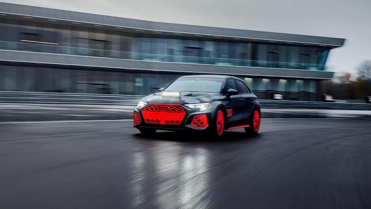 Audi RS 3 driving experience fährt auf einer Strecke, im Hintergrund befindet sich ein großes Gebäude