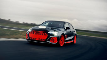 Audi RS 3 driving experience fähr bei grauem Himmel auf einem Trainingsgelände durch eine Kurve.