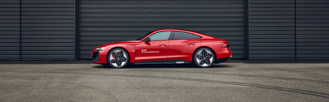 Red Audi RS e-tron GT performance stands in front of a wall (side view)