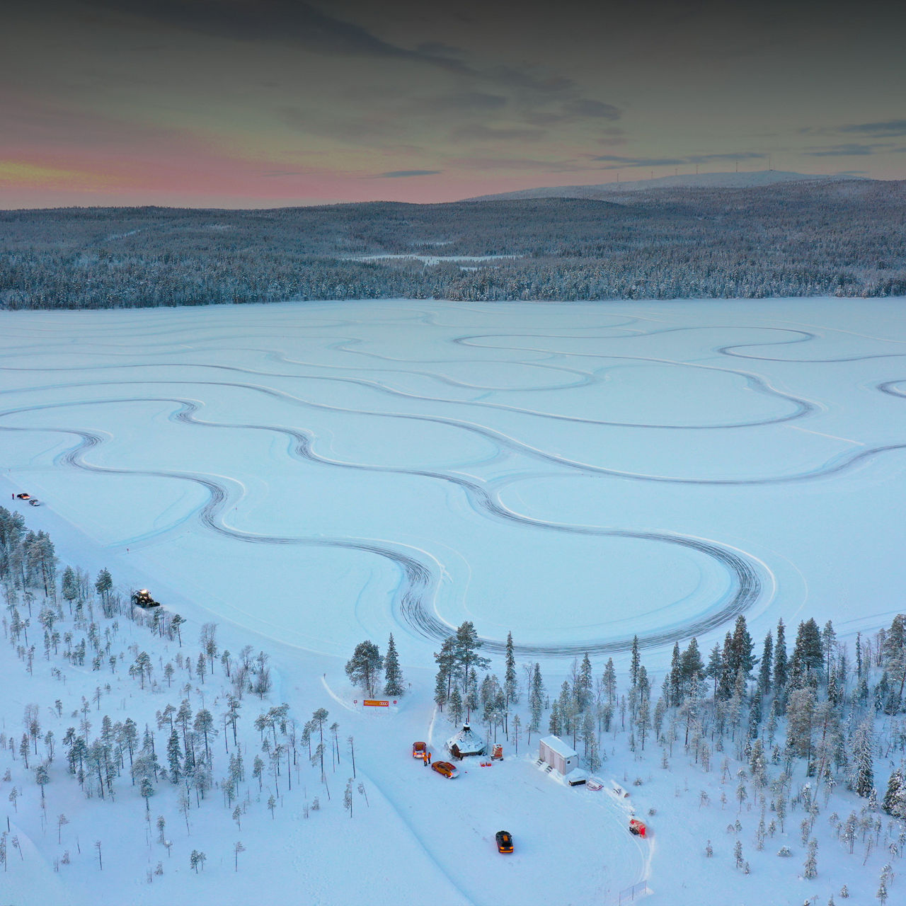 Winterliche Landschaft mit verschneiter Fahrbahn und mehreren Fahrzeugen auf einem Testgelände.