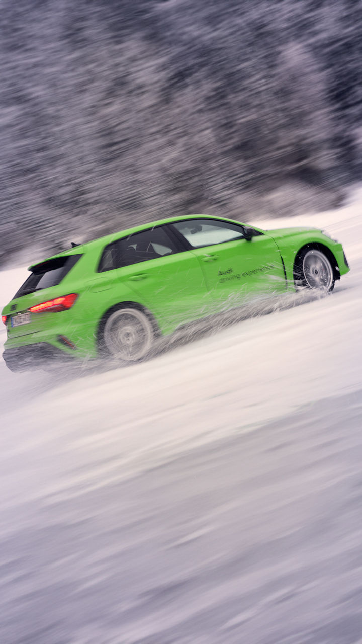 Light green Audi RS 3 Sportback whirls up water and snow while drifting in the snow.