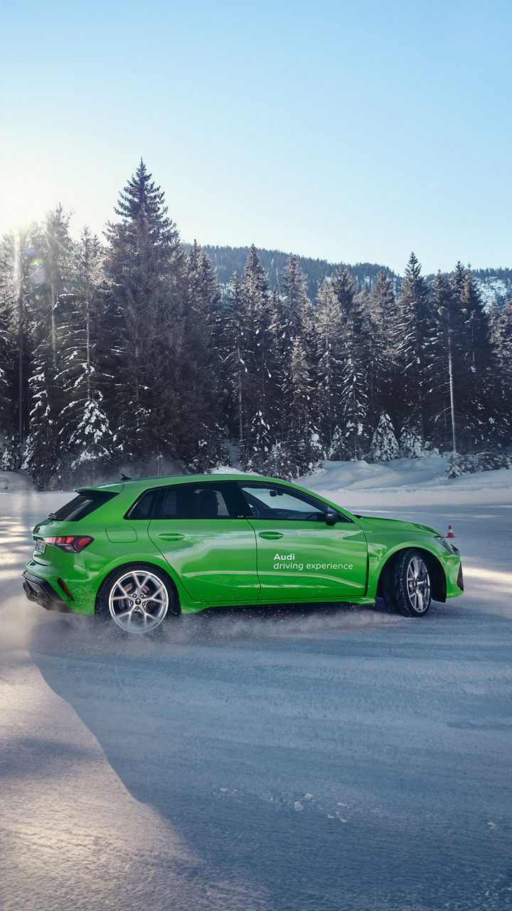 Light green Audi RS 3 Sportback with Audi driving experience logo drifting in the snow