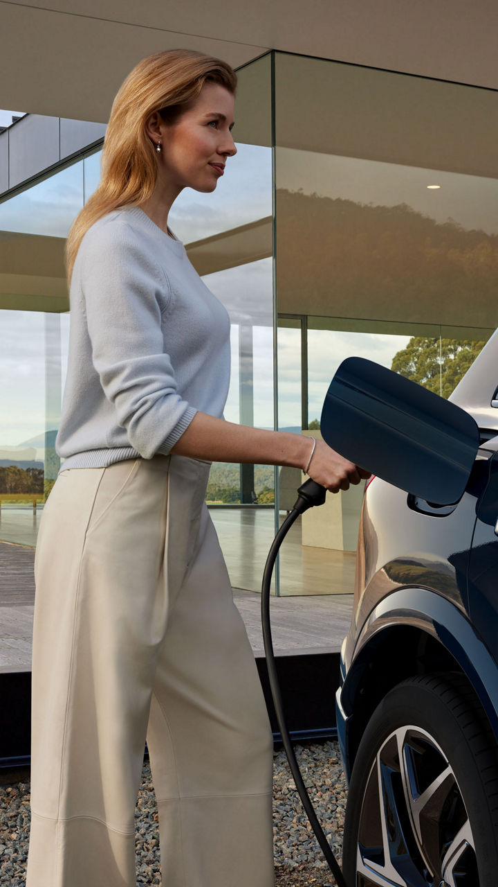Frau lädt Elektroauto