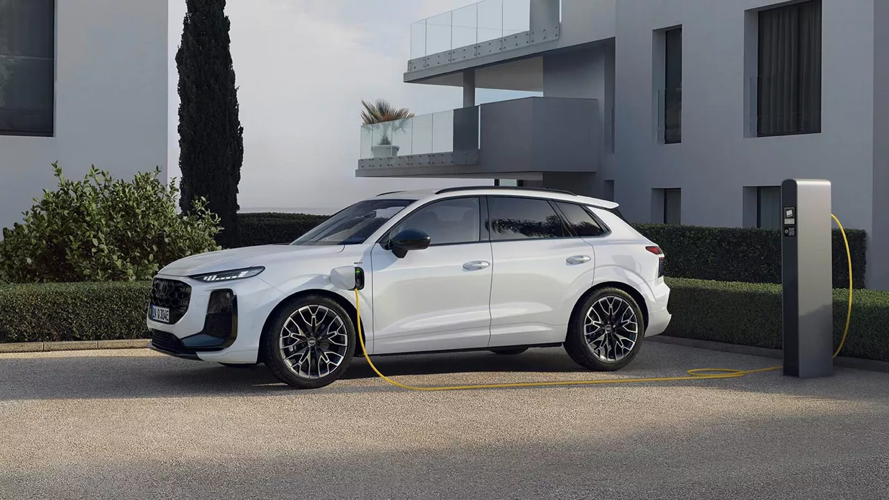 Ein weißer Q3 SUV e-hybrid ist an einer Ladesäule angeschlossen
