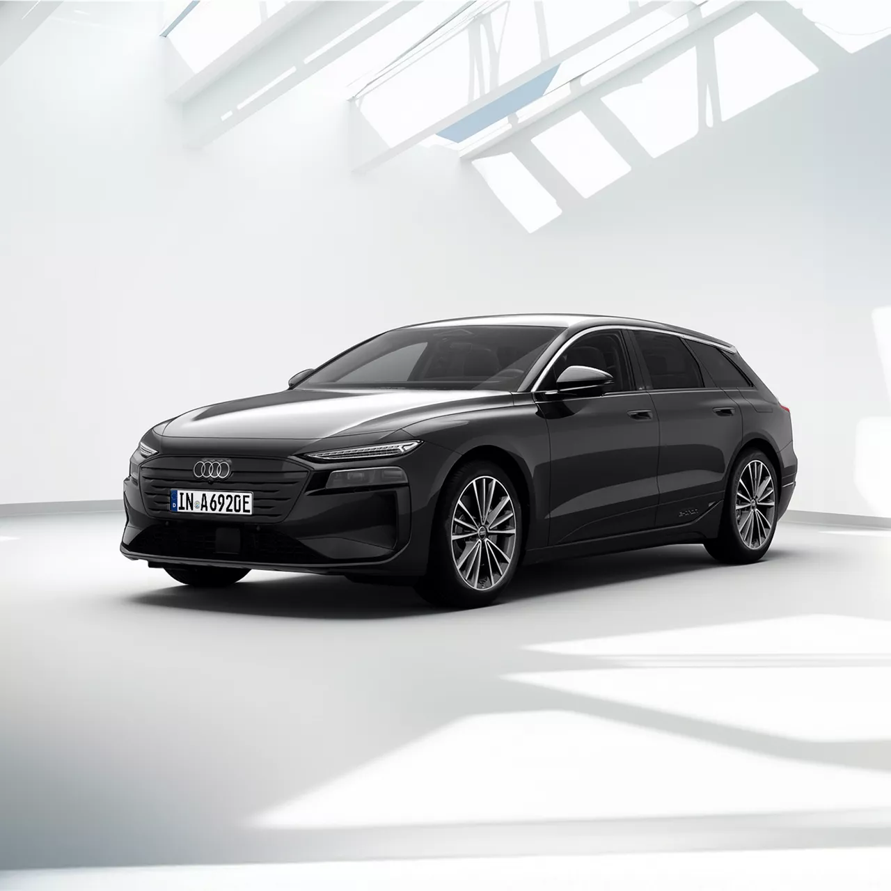 Grauer Audi A6 Avant e-tron steht vor einem modernen Gebäude bei Sonnenuntergang.