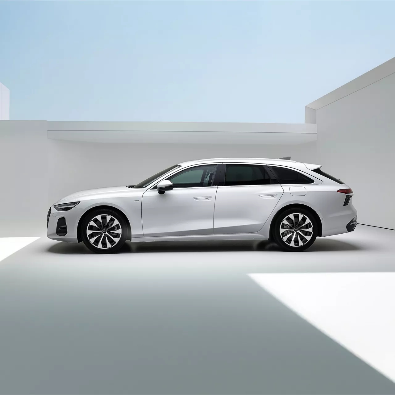 Weißer A6 Avant e-hybrid steht seitlich von hinten vor einer Ladestation