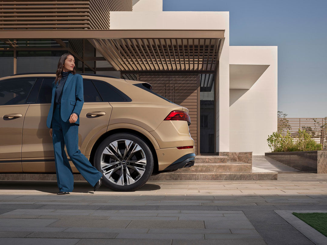 Eine Frau läuft neben einem Karamell farbenden Audi 