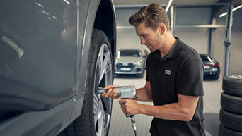 Mann repariert einen Reifen im Autohaus