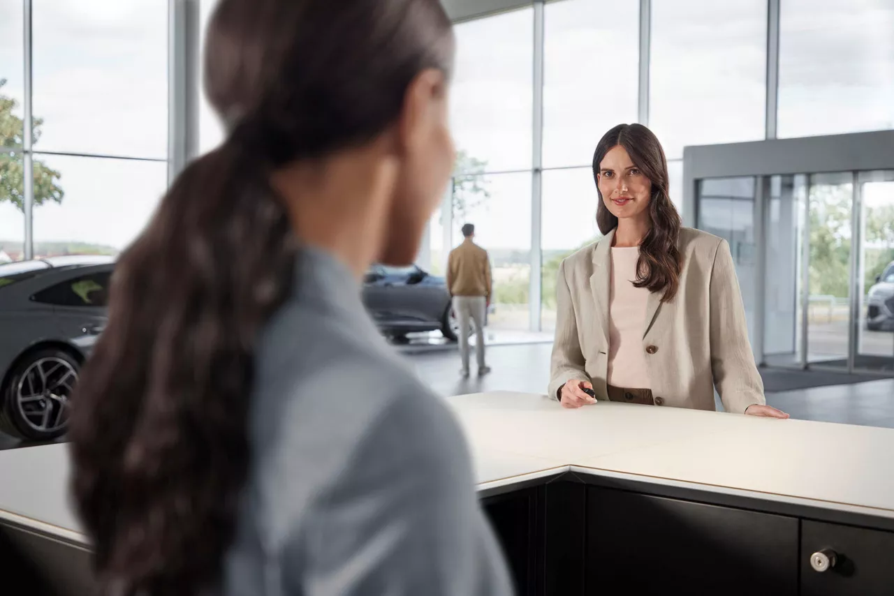Frau steht an Counter und redet mit Serviceassistentin