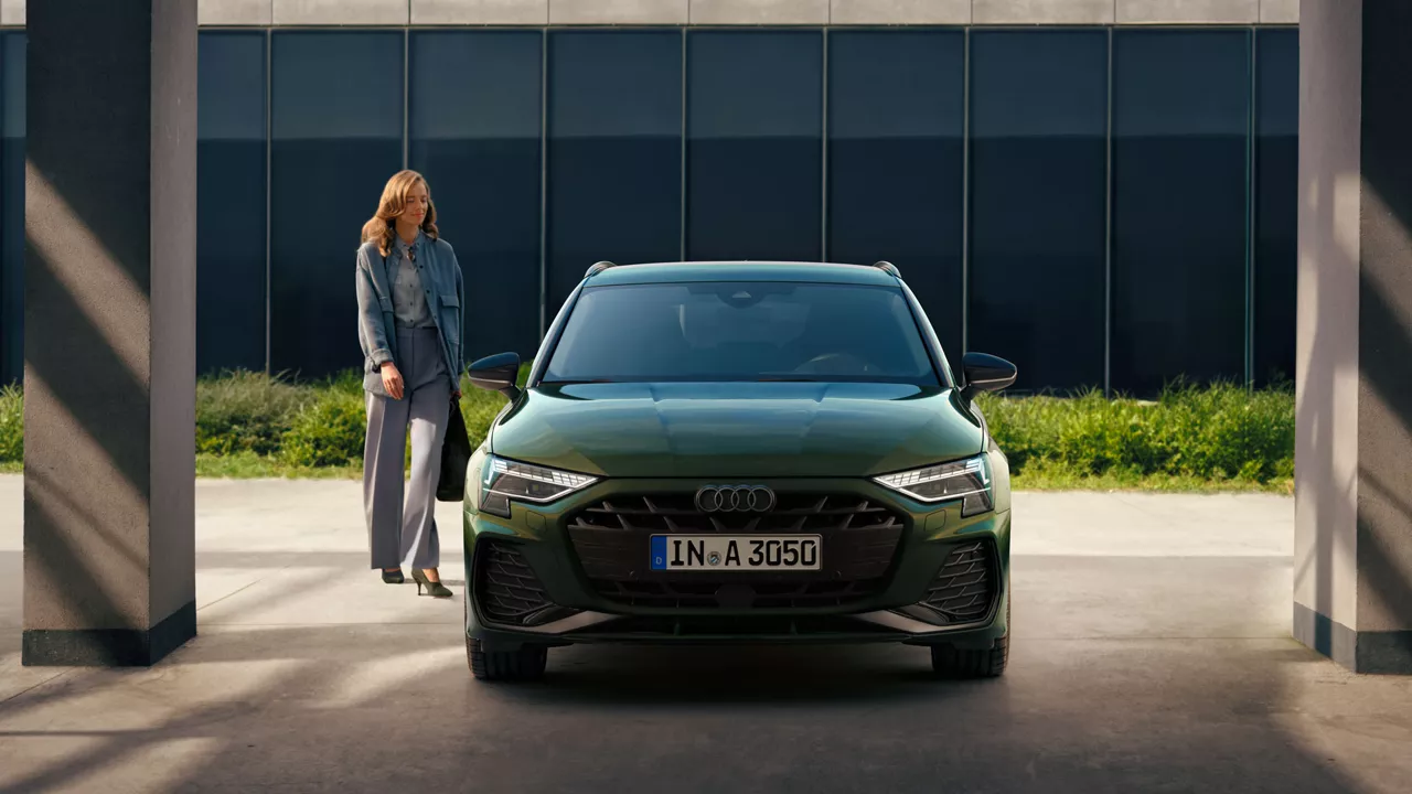 Eine Frau geht auf einen grünen Audi zu