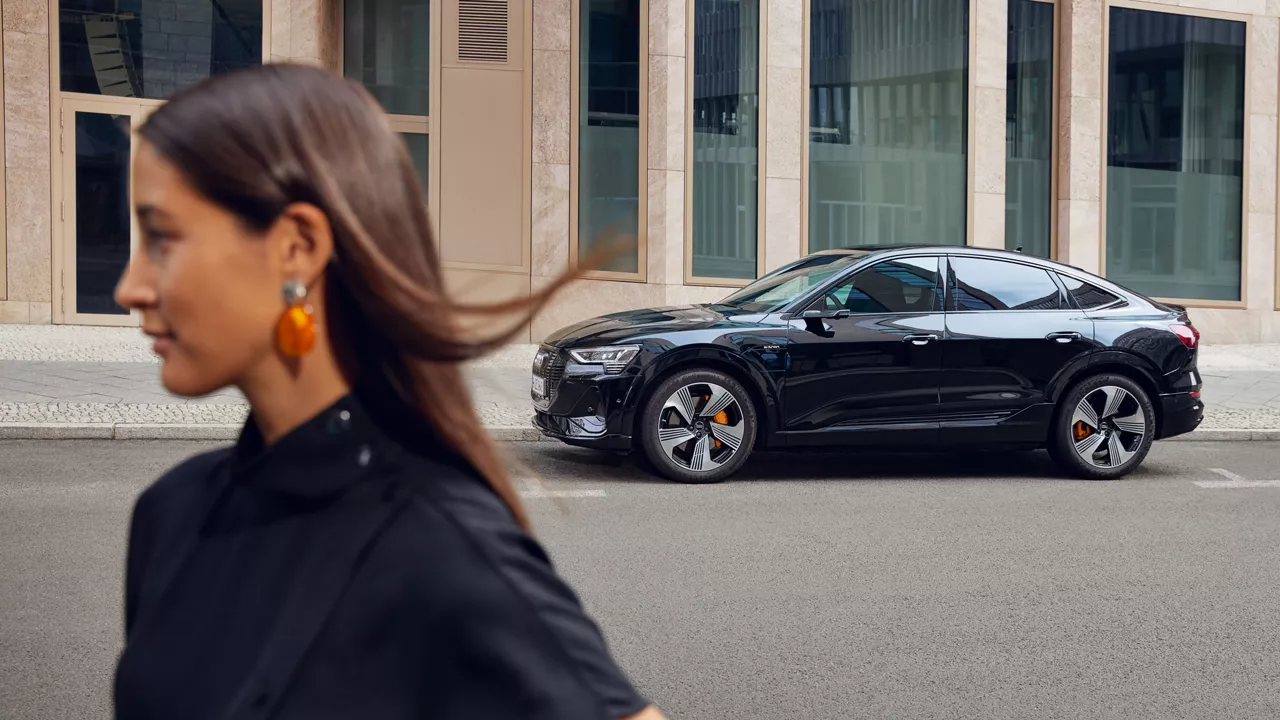 Eine Frau läuft neben einem schwarzen Audi