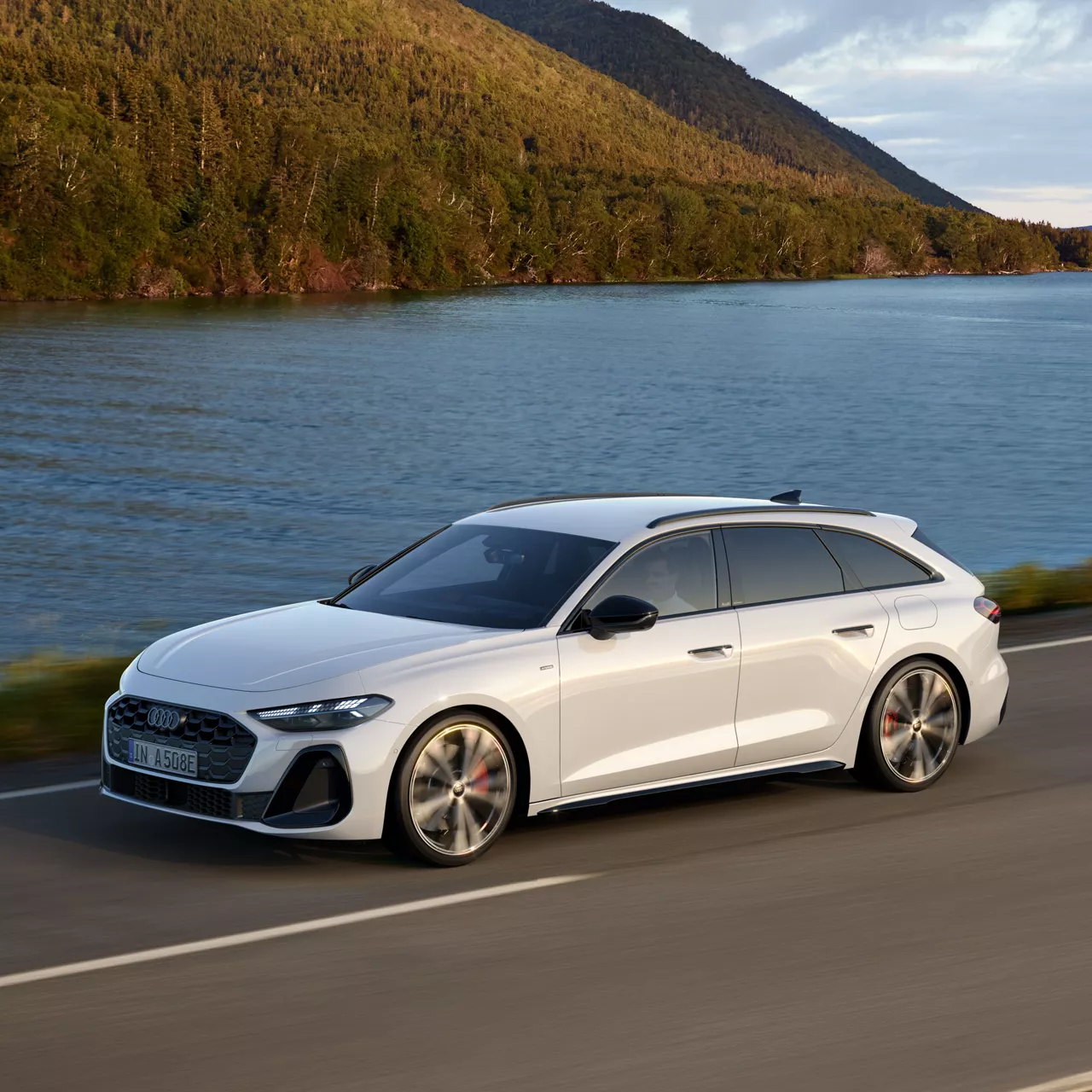 Ein weißer Audi A5 e-hybrid auf einer Straße direkt am Wasser.