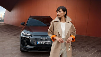 Eine Frau steht vor einem schwarzen Audi 