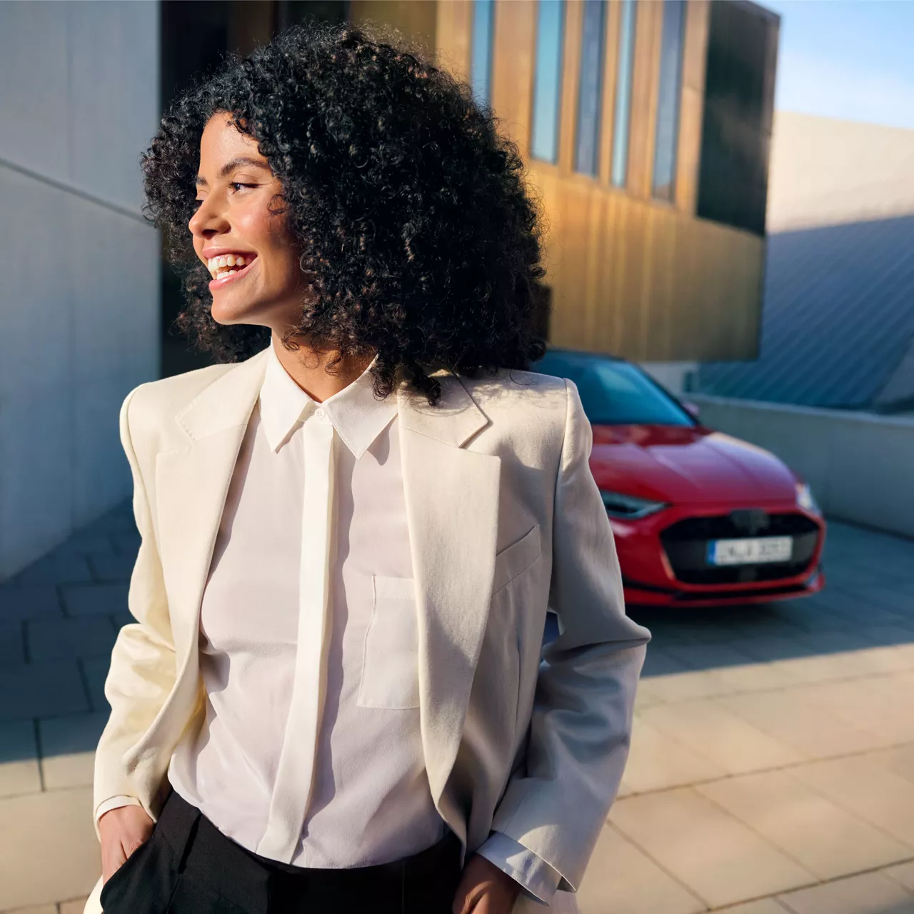 Eine Frau lacht, im Hintergrund steht ein roter Audi
