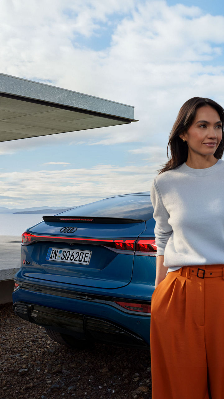 Eine Frau steht vor einem blauen Audi e-tron