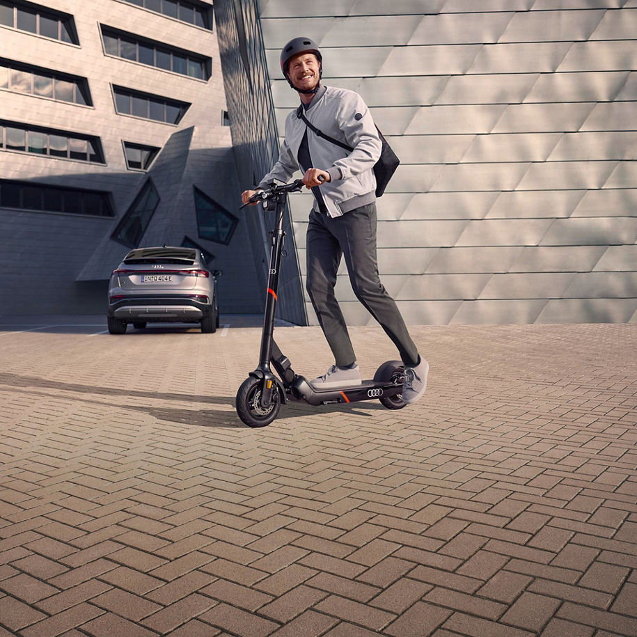 Ein Mann mit Helm auf fährt auf einem electric kick scooter von Audi