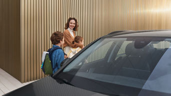 Eine Frau steht mit ihren beiden Kindern hinter einem Audi