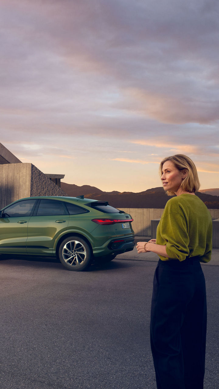 Eine Frau steht neben einem grünen Audi