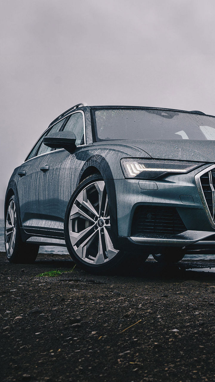 Ein Audi A6 steht am Meer im Regen