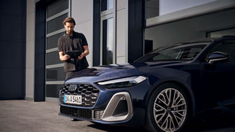 Ein Mann steht mit einem Tablet neben einem blauen Audi