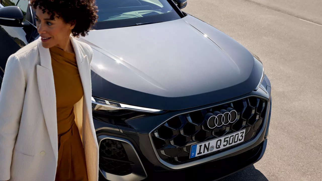 Eine Frau läuft vor einem blauen Audi
