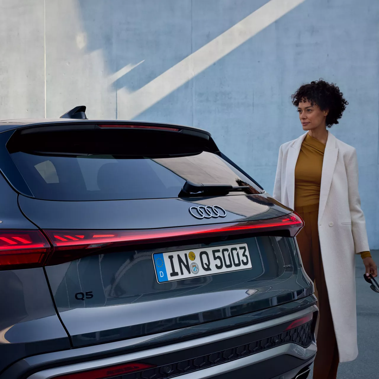 Eine Frau steht hinter dem Heck eines Audi Q5 SUVs