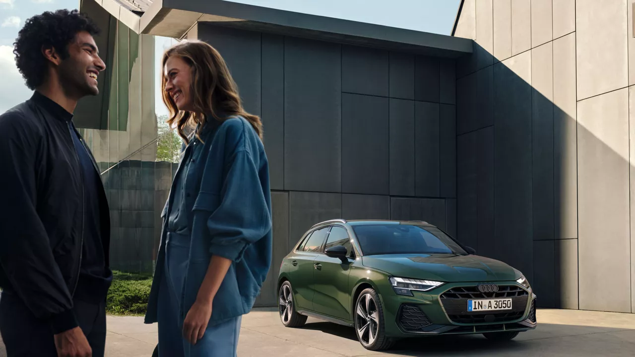 Zwei Leute stehen vor einem grünen Audi