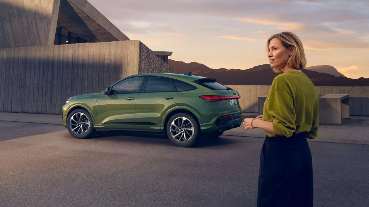 Eine Frau steht neben einem grünen Audi