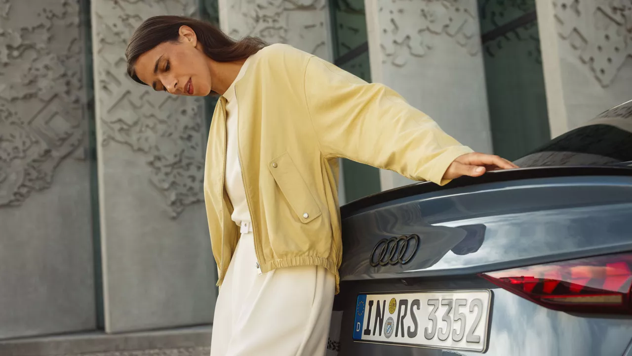 Frau lehnt sich an einem Audi