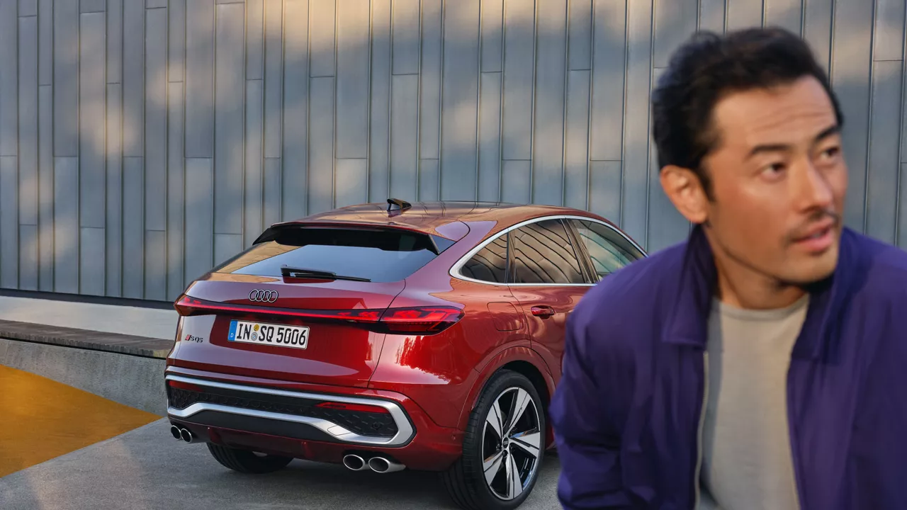 Ein Mann neben einem roten Audi