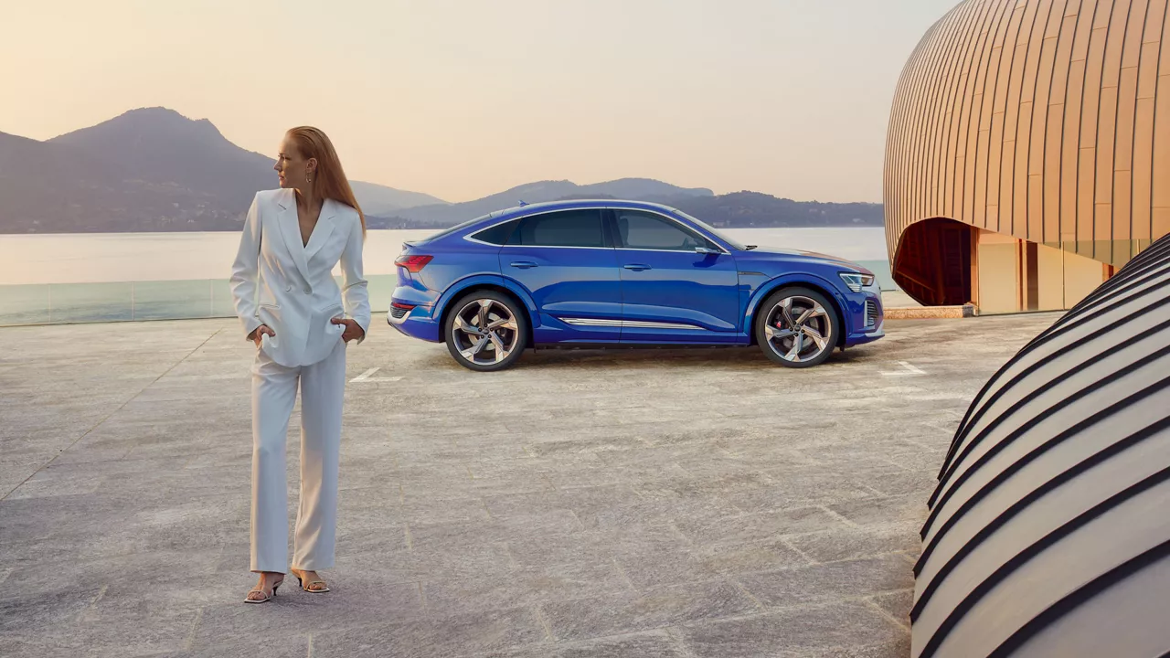 Eine Frau steht vor einem blauen Audi