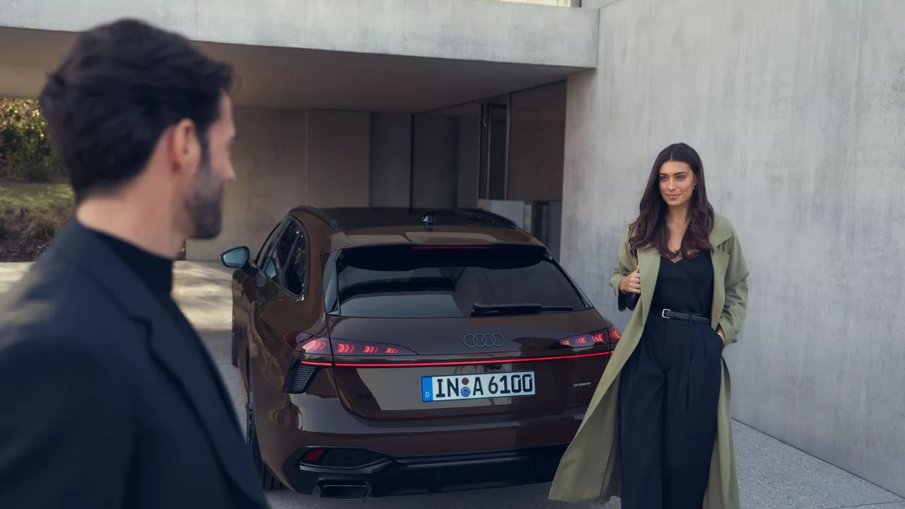 Ein Mann und eine Frau stehen vor einem braunen Audi