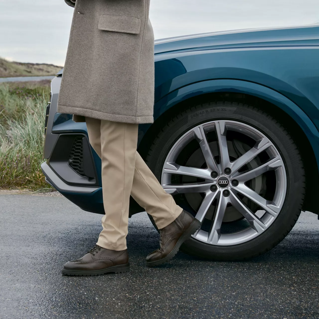 Die Beine eines Mannes vor einem Audi