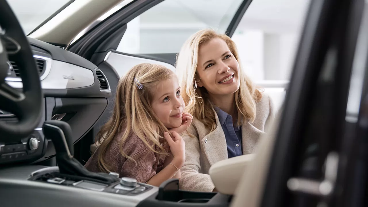 Kind und Frau schauen sich Auto von innen an