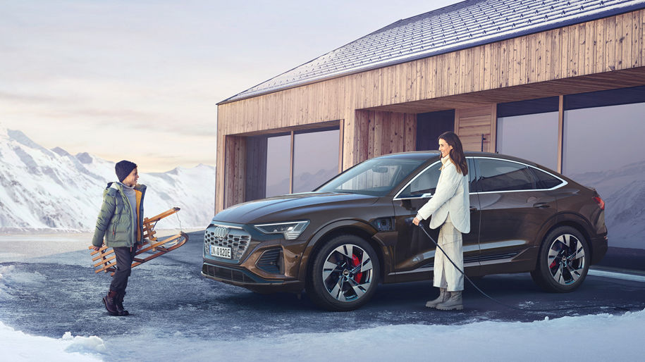 Mann und Kind laden einen Audi im Winter
